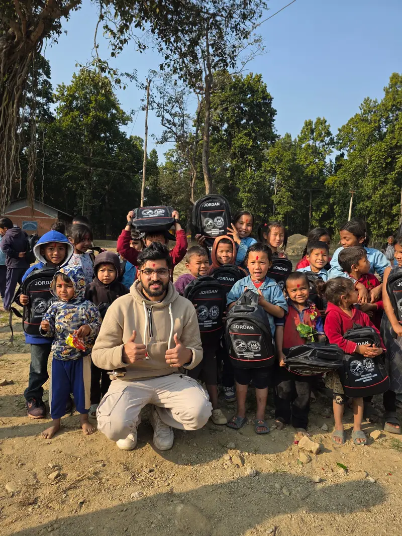 A volunteer with children holding new school bags at an outdoor community programme.